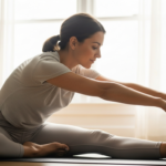 Calm lifestyle photograph of a woman doing gentle yoga stretching by a bright window in the morning, hormone-balance wellness mood, soft natural light